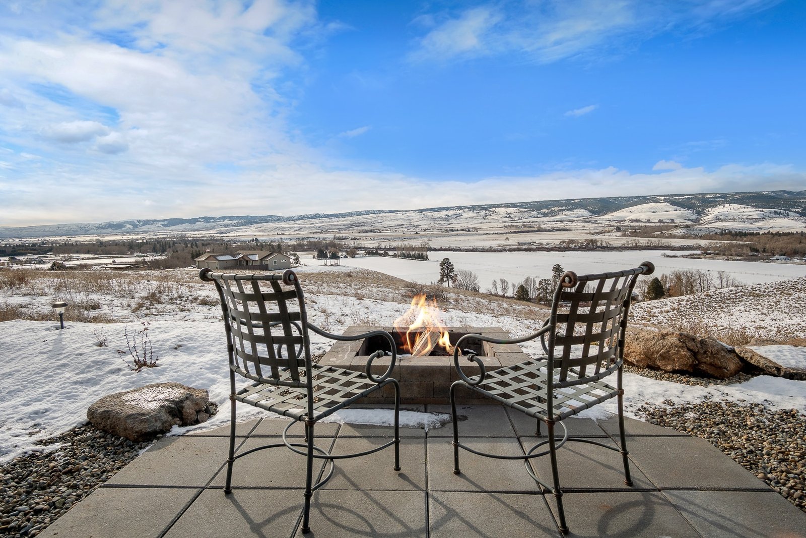 Chairs by firepit overlooking snowy landscape
